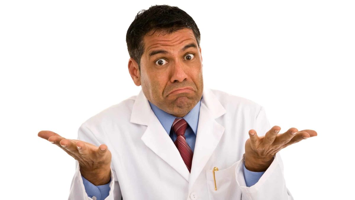 A male doctor wearing a white doctor's coat shrugs and holds his hands up to indicate the unimpressive CSL share price as a result of OOVID-19