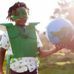 boy dressed as an eco warrior and holding a globe.