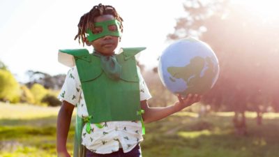 boy dressed as an eco warrior and holding a globe.