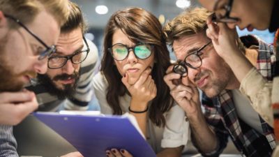 Group of thoughtful business people with eyeglasses reading documents in the office.