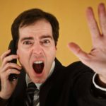 A man using a phone shouts and puts his hand out in a stop motion indicating the Yancoal trading halt today