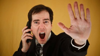 A man using a phone shouts and puts his hand out in a stop motion indicating the Yancoal trading halt today