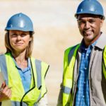 Two miners standing together with a smile on their faces.