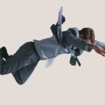A man in a business suit hangs in mid air facing the floor as he plunges to the ground.