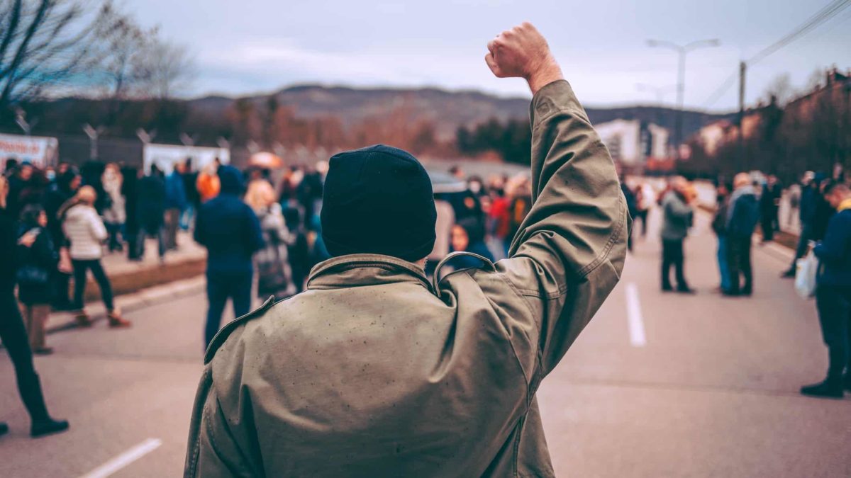 A man protests in the street with raised fist.