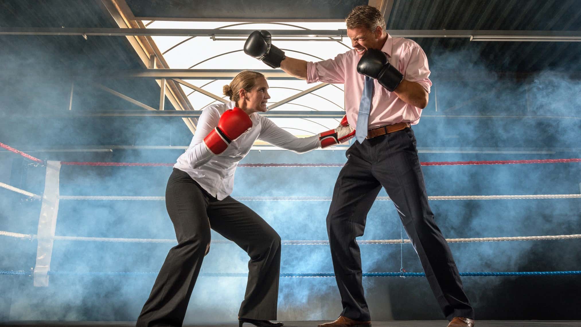 A woman in a business suit and a man in a business suit boxing in a ring.
