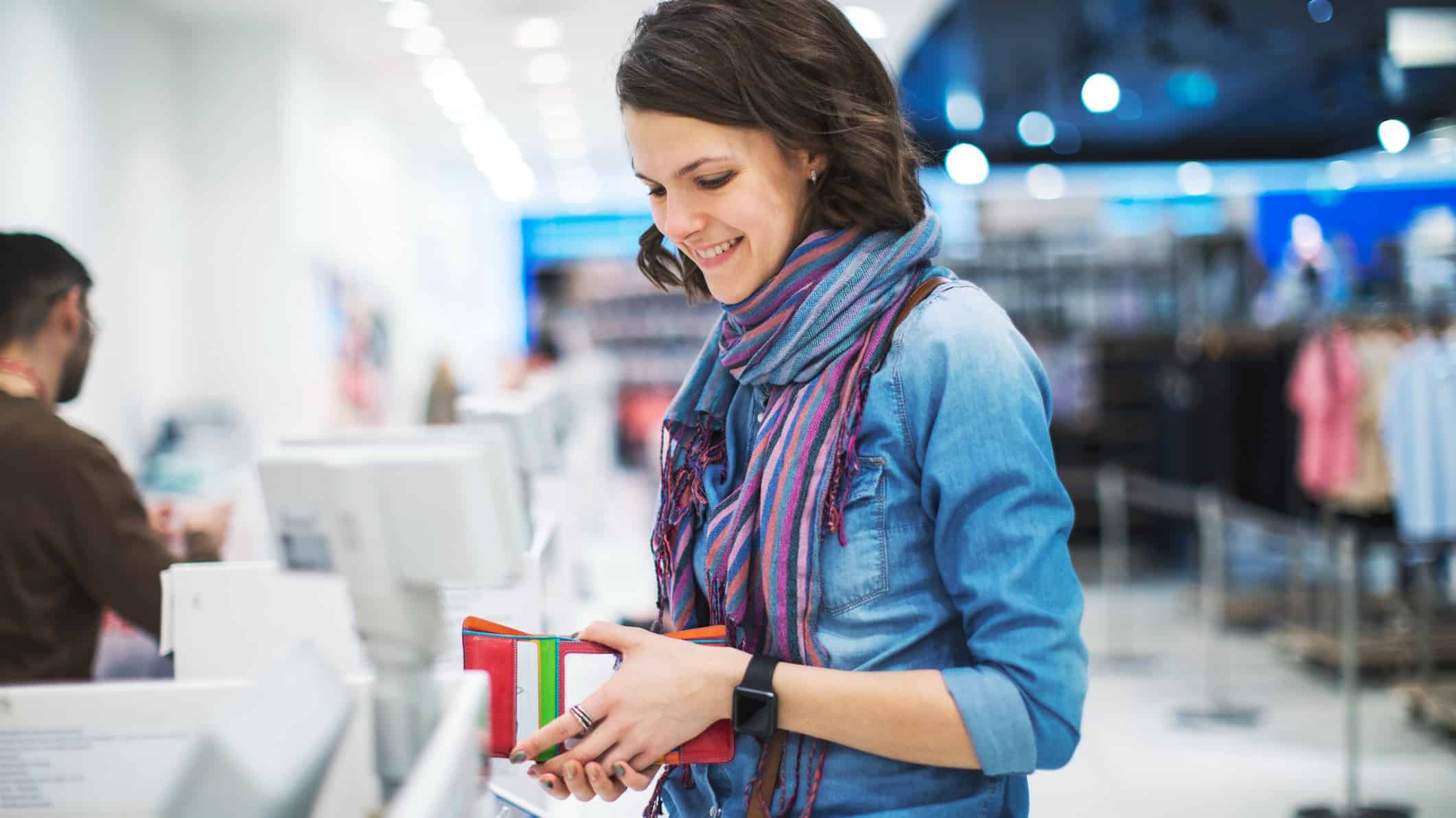 A young woman in a retail shop holding her wallet open ready to pay for her items using Afterpay