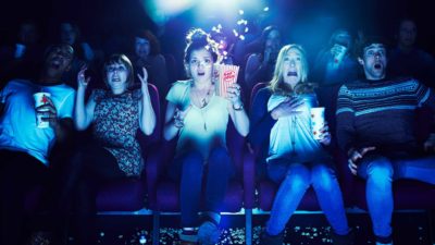 A group of cinema-goers looked scared as they watch a movie.