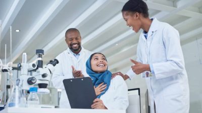 A group of three scientists talking excitedly while working in a lab on a diabetes test developed by Proteomics International Laboratories which is an ASX share tipped to explode by Alto Capital