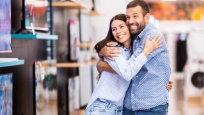 A happy couple hug each other as shopping resumes in an electronics store
