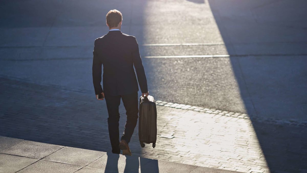 Businessman walking down staircase with suitcase, at sunrise