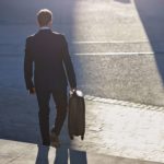 Businessman walking down staircase with suitcase, at sunrise