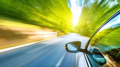 Tesla car screams down a road surrounded by blurred greenery