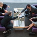 A group of business executives shake hands in a lounge.