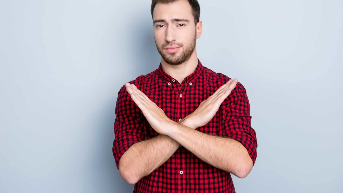 A man stands with his arms crossed in an X shape.