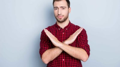 A man stands with his arms crossed in an X shape.