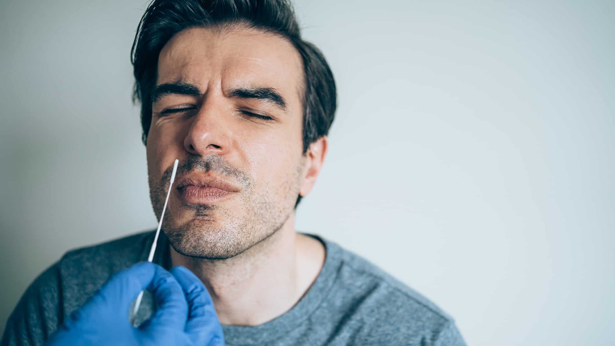 A man screws up his face as his nose is swabbed for a COVID test.