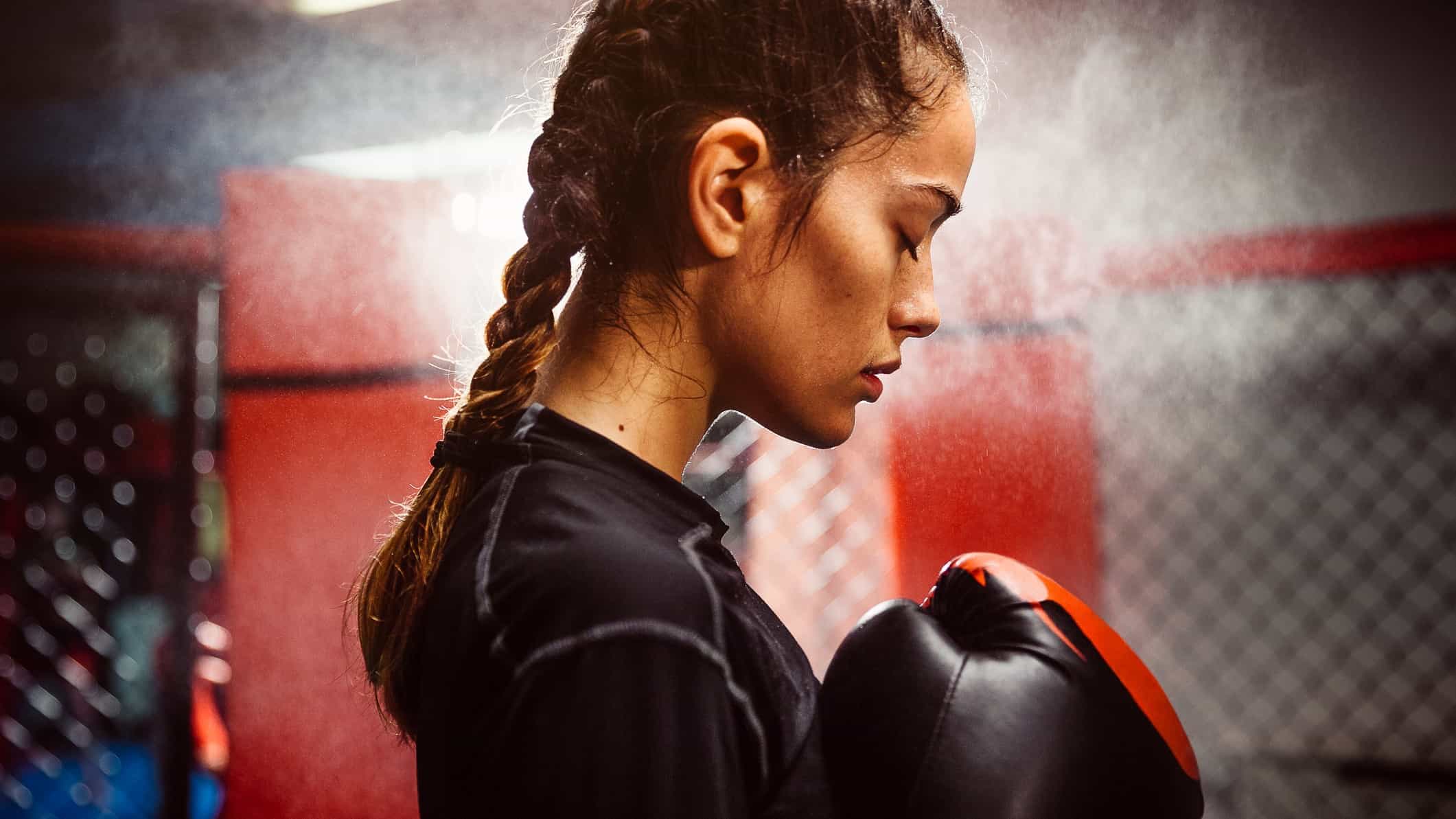 A female boxer focuses with her eyes closed, maintaining control of her thoughts.
