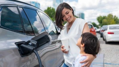 Woman And Child Charging Electric Car.