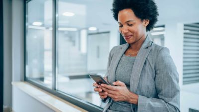 A female executive smiles as she carries out business on her mobile phone.