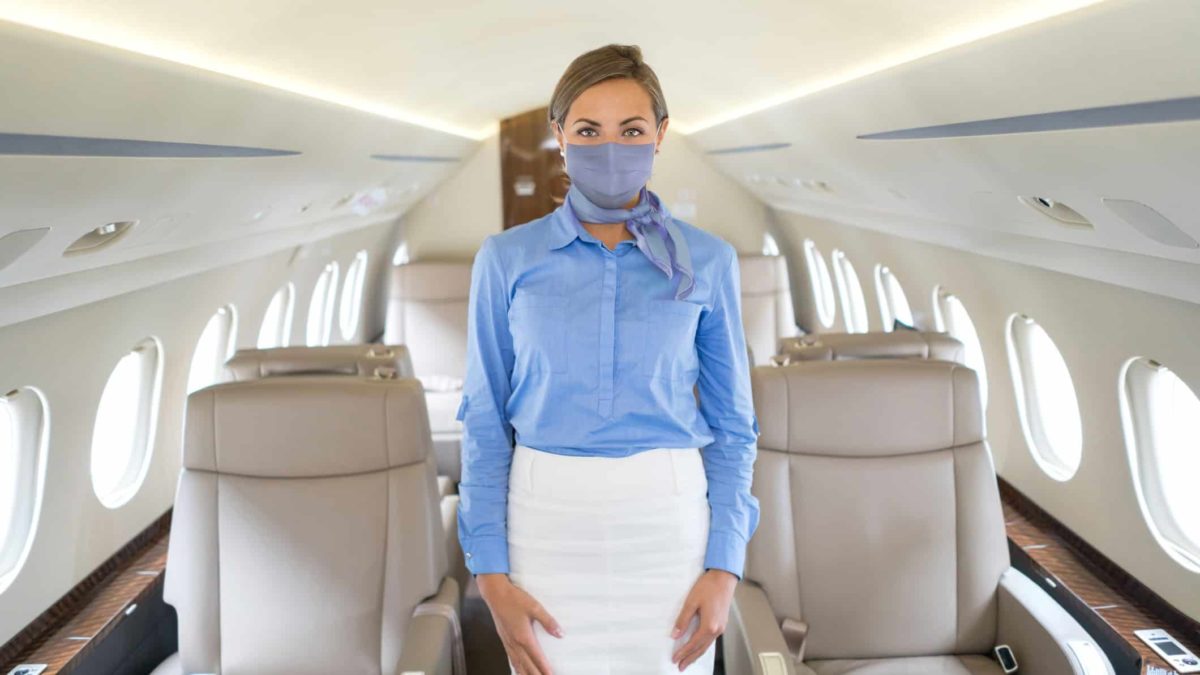 Airplane attendant standing in a private plane with a mask