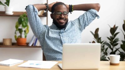 a man sits back from his laptop computer with both hands behind his head feeling happy to see the Brambles share price moving significantly higher today