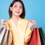a woman with lots of shopping bags looks upwards towards the sky as if she is pondering something.