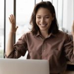 a woman holds her hands up in delight as she sits in front of her lap