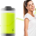 A woman stands next to a large green battery smiling and eating an apple with a lifting green arrow line in the background, indicating rising stock prices.