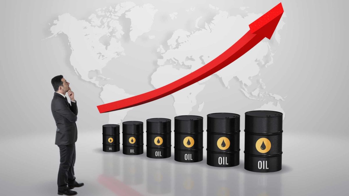 A graphic depicting a businessman in a business suit standing with his hand to his chin looking at a large red arrow pointing upwards above a line up of oil barrels againist the backdrop of a world map.