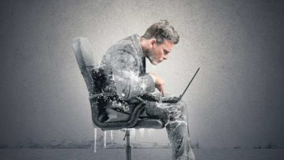 A man sits in a chair hunched over a laptop and covered head to toe in frozen icicles to represent Envirosuite's trading halt