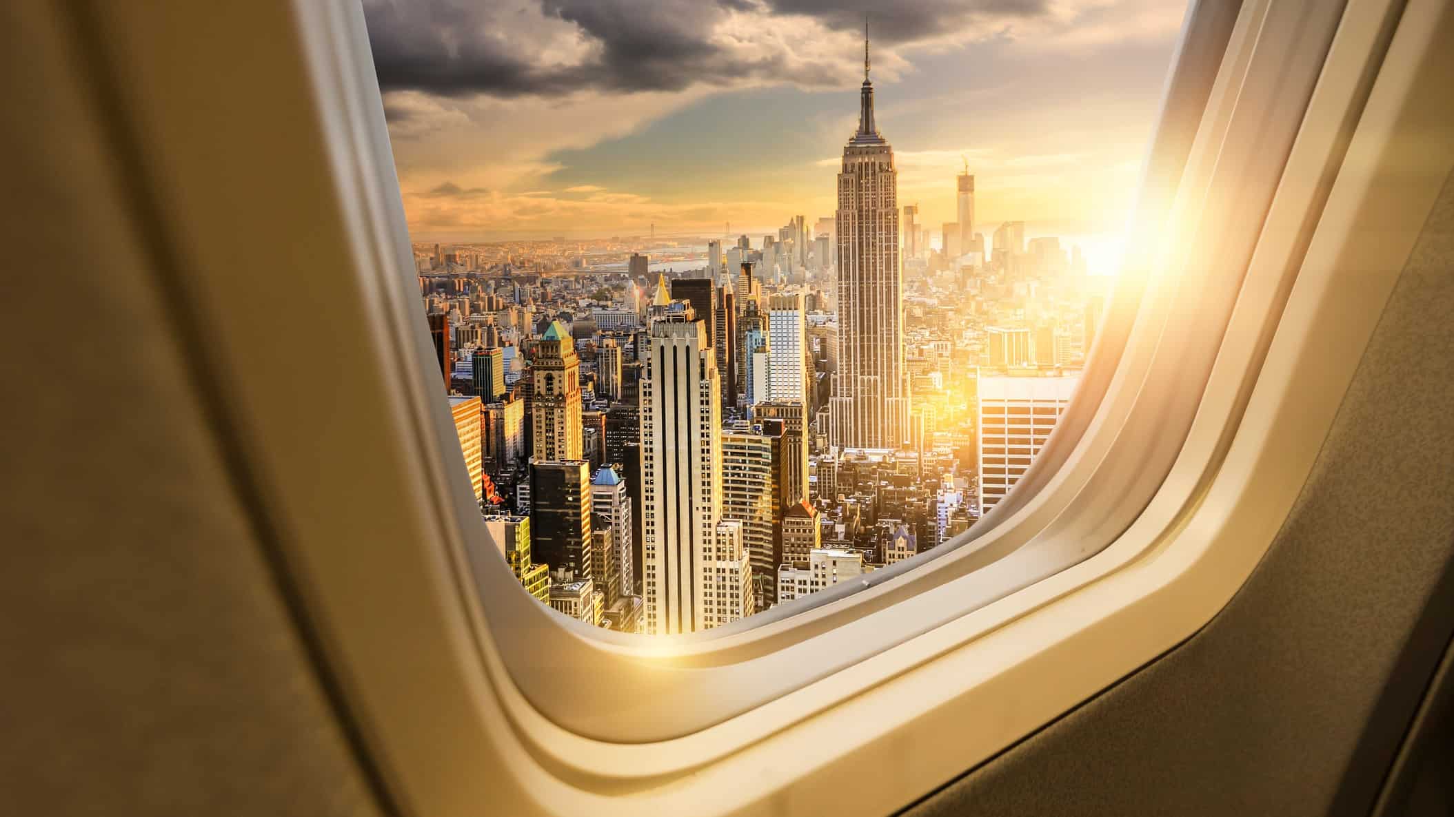 A view of New York at sunrise looking from inside an aeroplane window.