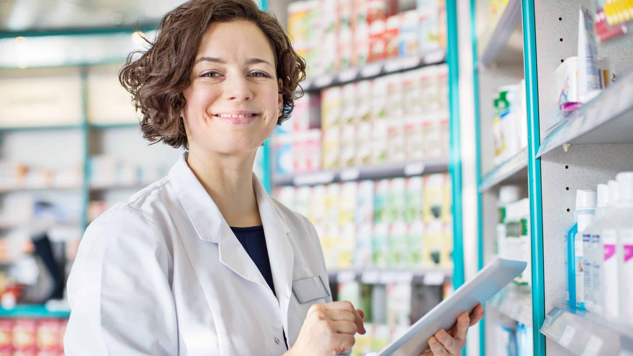Female pharmacist smiles with a digital tablet.