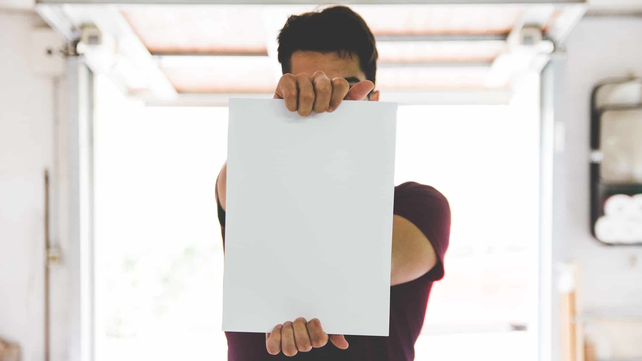 A person holds out a blank piece of paper.