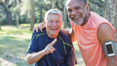 Two older male friends using tech to record their run.