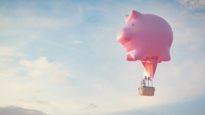 A giant inflatable pig hot air balloon soars high in the sky.