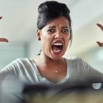 A woman screams and holds her hands up in frustration.