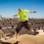 A Cimic construction worker leaps high in the air on a building site.