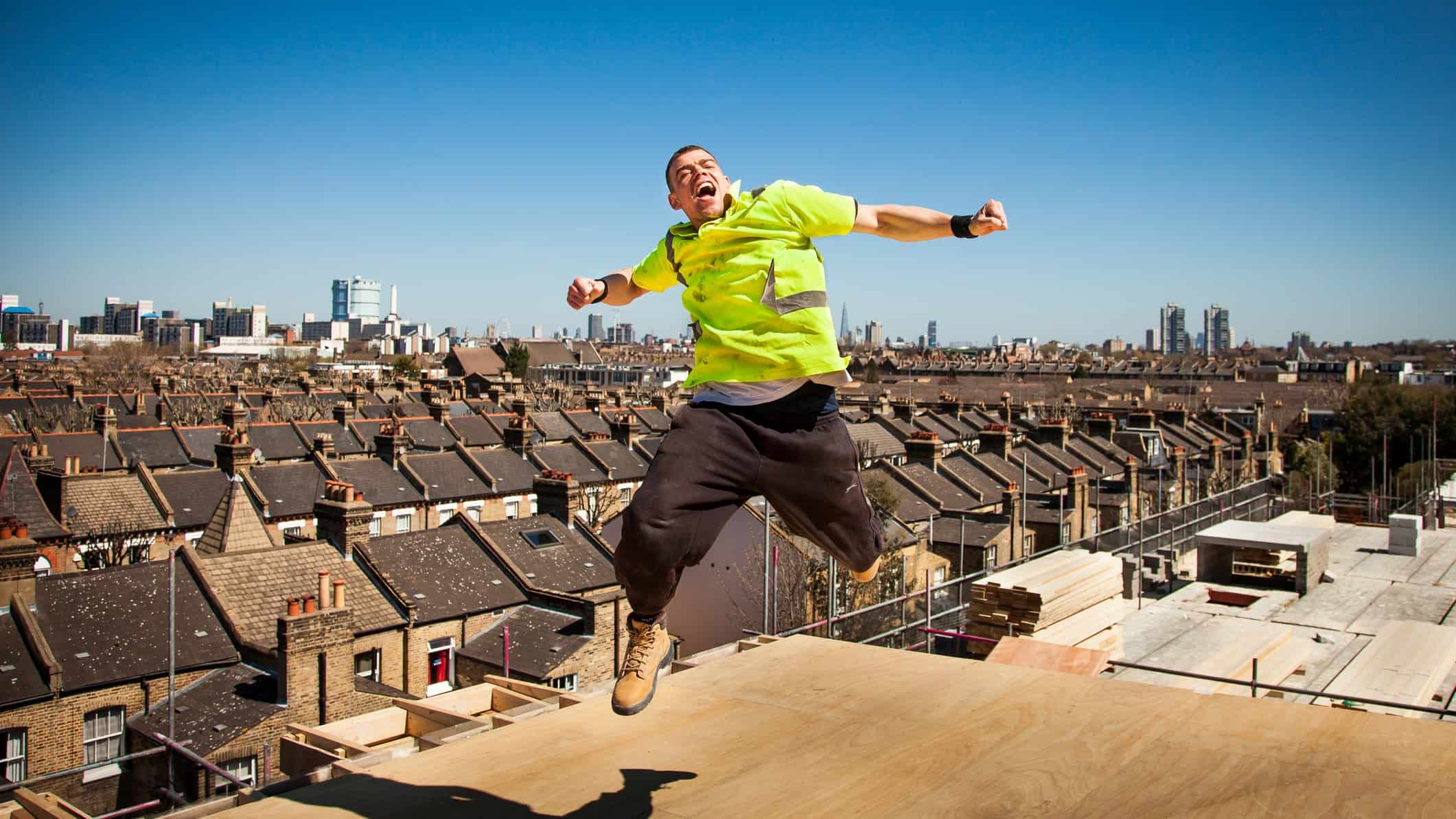 A Cimic construction worker leaps high in the air on a building site.