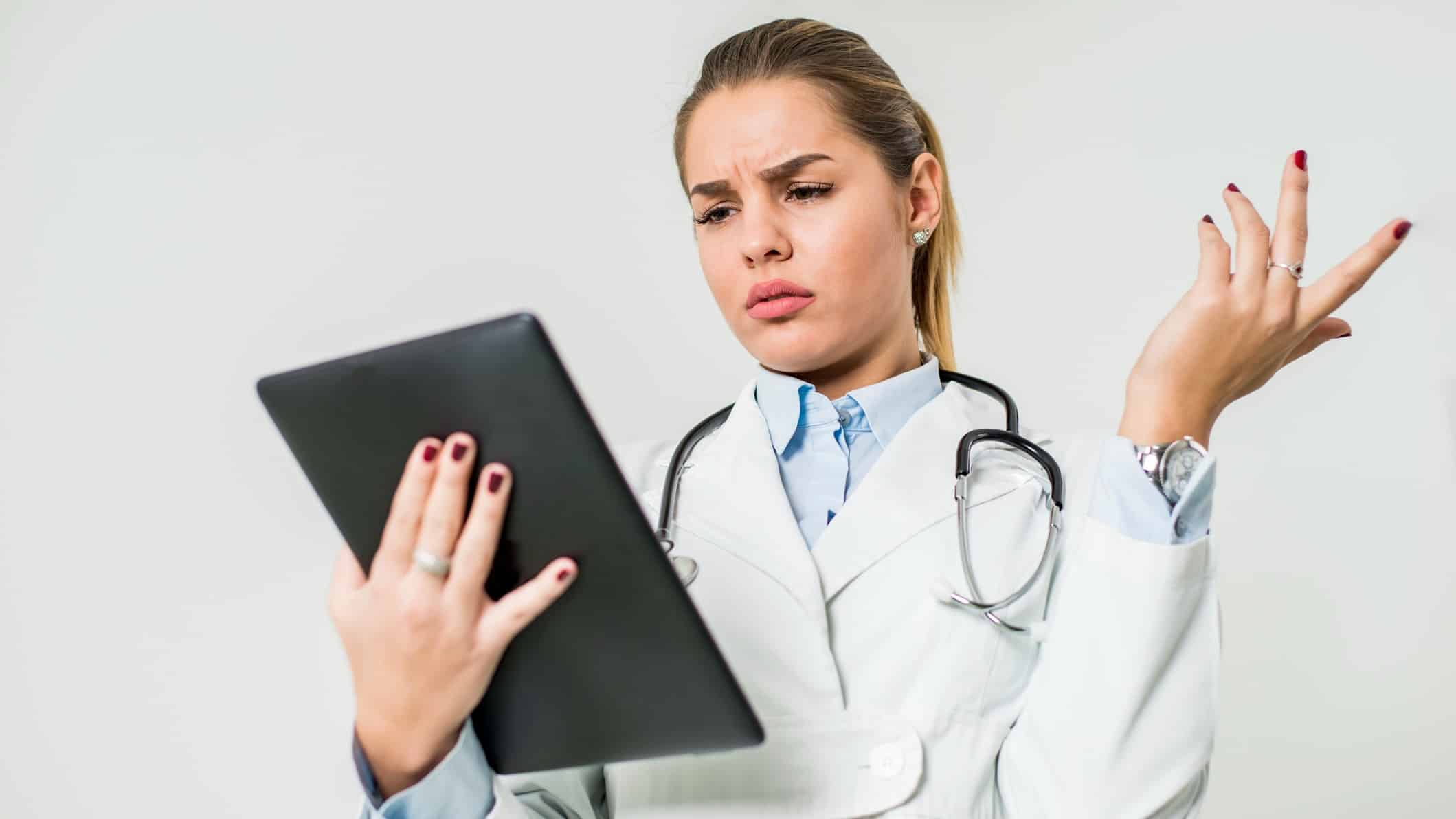 young female doctor with digital tablet looking confused.
