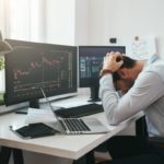 Man with his head in his head because of falling share price.