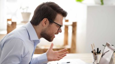 A frustrated male investor frowns with his hands and arms open asking why the share price has dropped today.