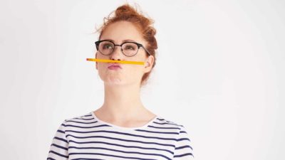 A woman holds a pencil on her nose and contemplates an unsatisfactory result.