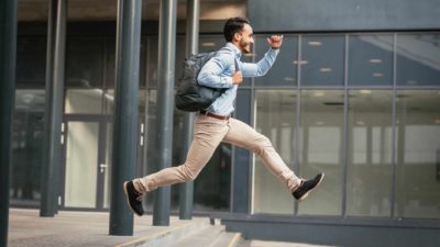 Man leaps as he runs along the street.