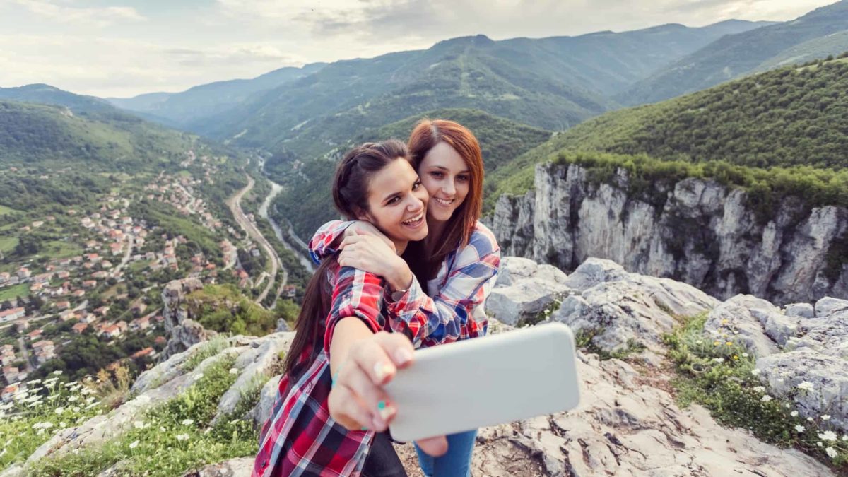 Happy girls taking selfie on a mountain peak.