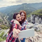 Happy girls taking selfie on a mountain peak.