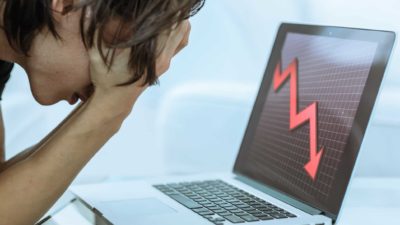 Sad investor watching the financial stock market crash on his laptop computer.