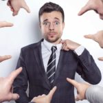 Several fingers point at stressed looking man in the middle.