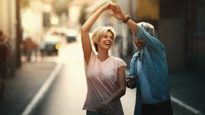A middle-aged couple dance in the street to celebrate their ASX share gains