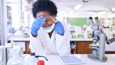 A female scientist sits at her desk looking stressed out while working in an AnteoTech lab.